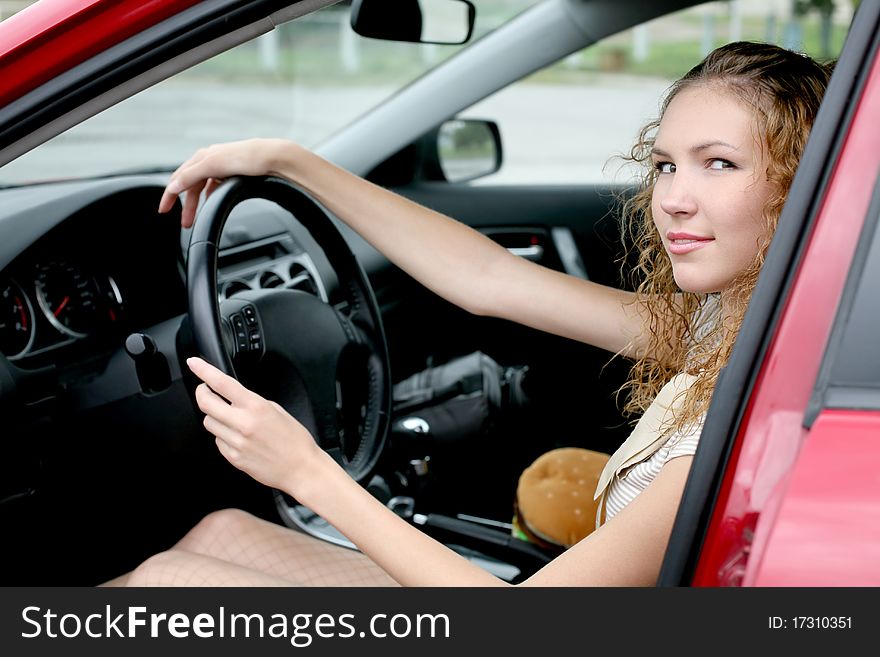 Young beautiful woman driver in red shiny car outdoors smiling. Young beautiful woman driver in red shiny car outdoors smiling