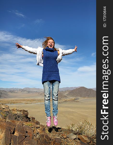 The jumping smiling girl against a mountain landscape in mongolia