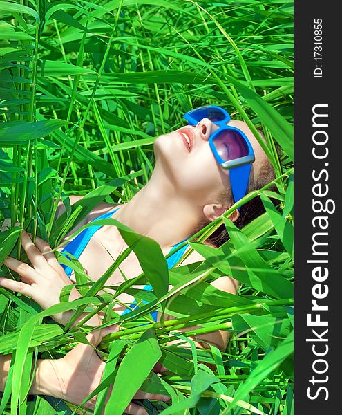 Portrait of a girl in the reeds in sunglasses and a blue bikini