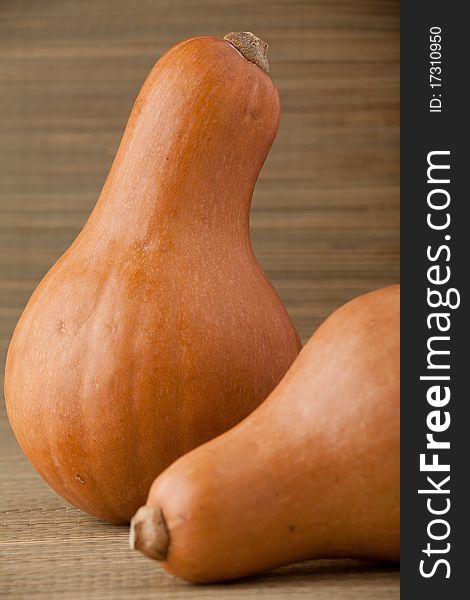 Two ripe orange pumpkins on straw woven surface