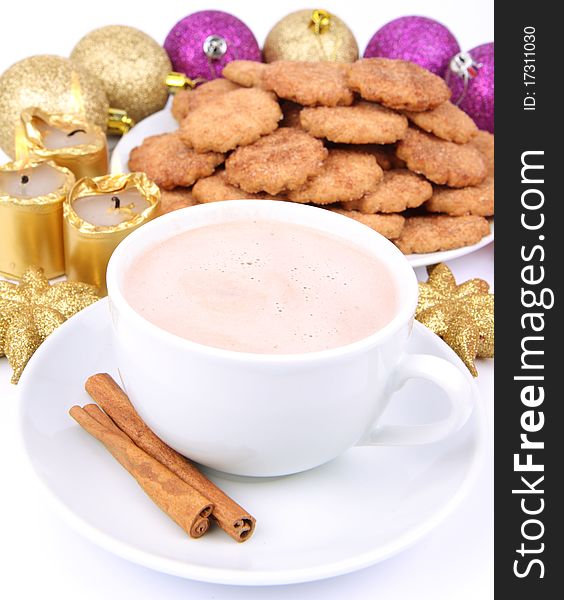 Cup of hot chocolate with cinnamon, cinnamon cookies and gold candles with christmas balls in the background. Cup of hot chocolate with cinnamon, cinnamon cookies and gold candles with christmas balls in the background