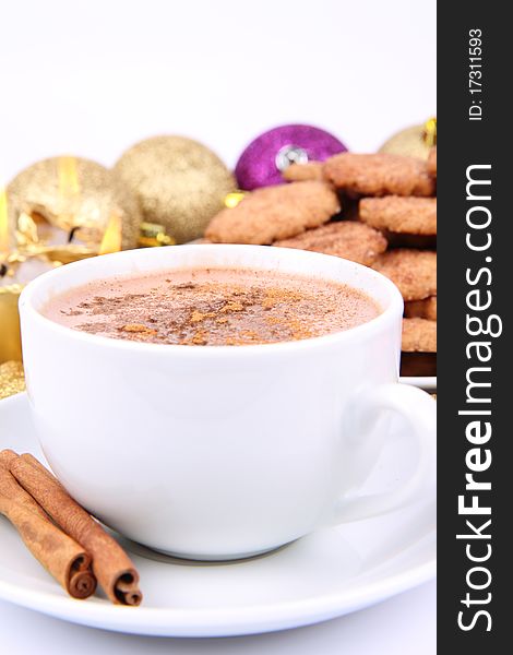 Cup of hot chocolate with cinnamon, cinnamon cookies and gold candles with christmas balls in the background. Cup of hot chocolate with cinnamon, cinnamon cookies and gold candles with christmas balls in the background