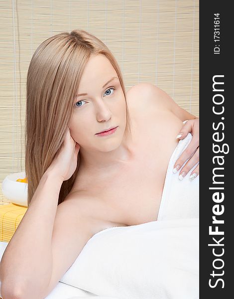 Woman in spa on white towel with blond hair