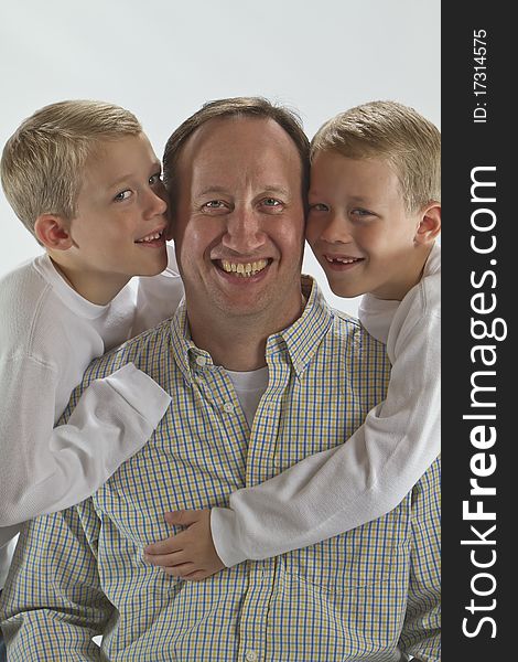 Happy dad gets a Fathers Day hug and a kiss from his identical twin sons