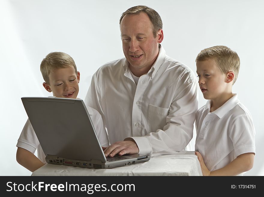 Modern Dad teaching his 6 years old boys how to use laptop computer