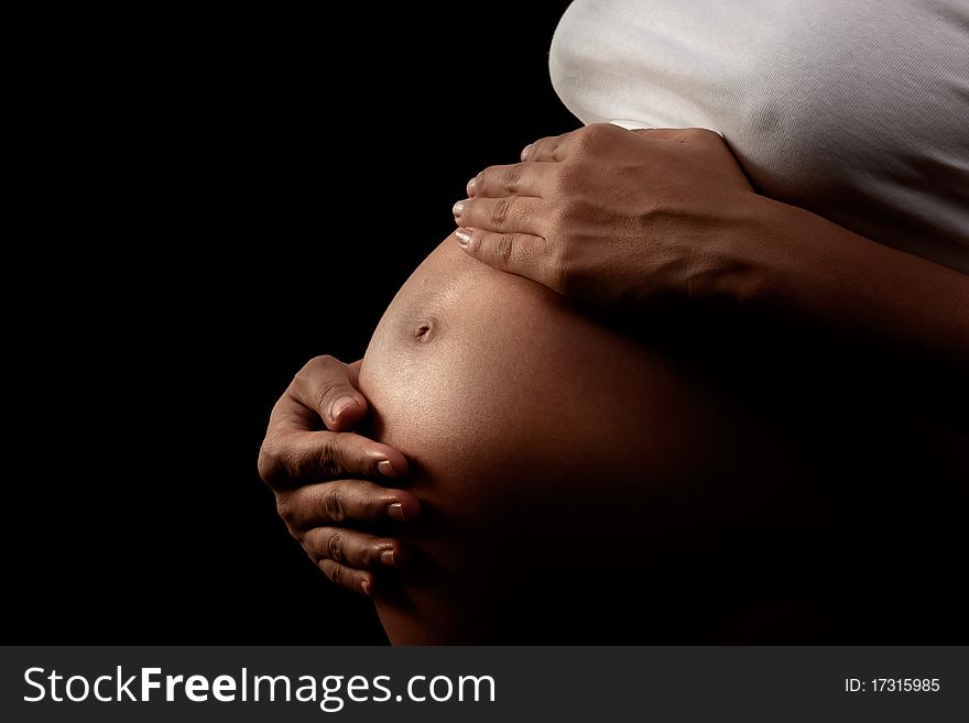 Pregnant woman holding her belly  over dark background. Pregnant woman holding her belly  over dark background