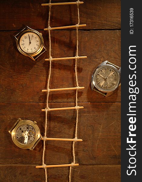 Rope ladder hanging on wooden background with old watches. Rope ladder hanging on wooden background with old watches