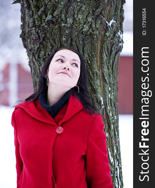 Young beautiful girl in the red coat leaning the tree. Young beautiful girl in the red coat leaning the tree