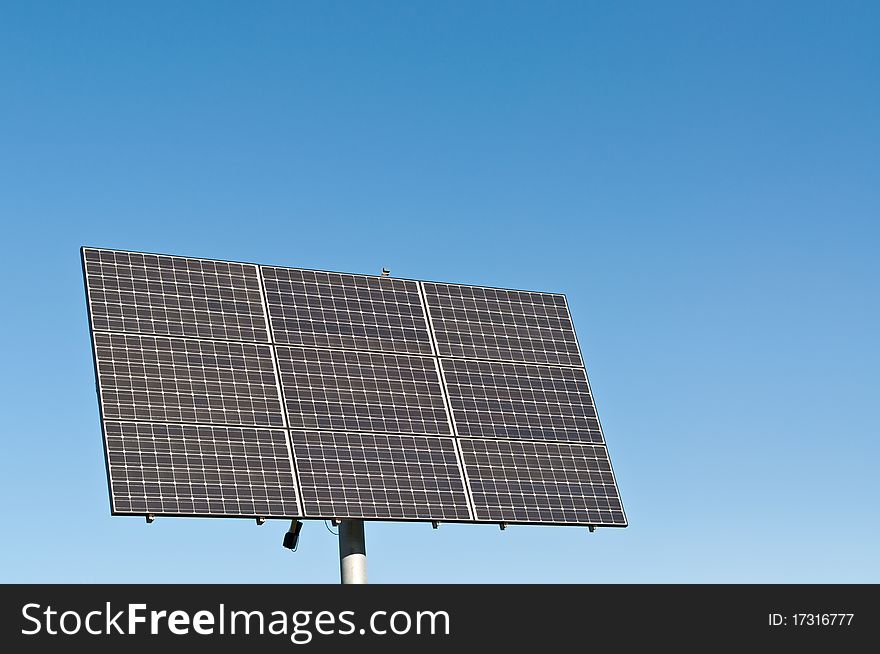 A photovoltaic solar panel array in a park with a deep blue sky in the background. Clean, renewable energy. A photovoltaic solar panel array in a park with a deep blue sky in the background. Clean, renewable energy.