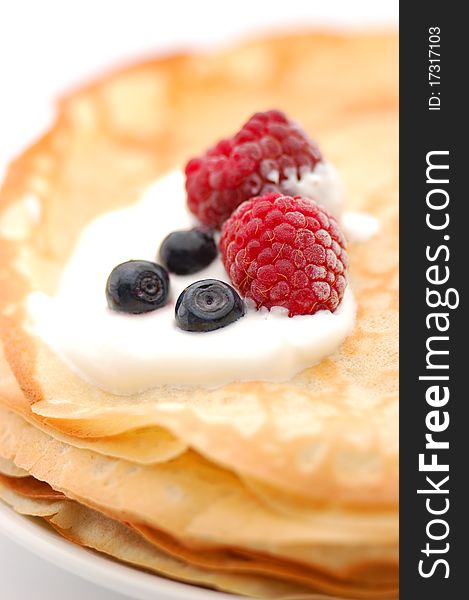 Pancakes topped with raspberries, bilberries and cream