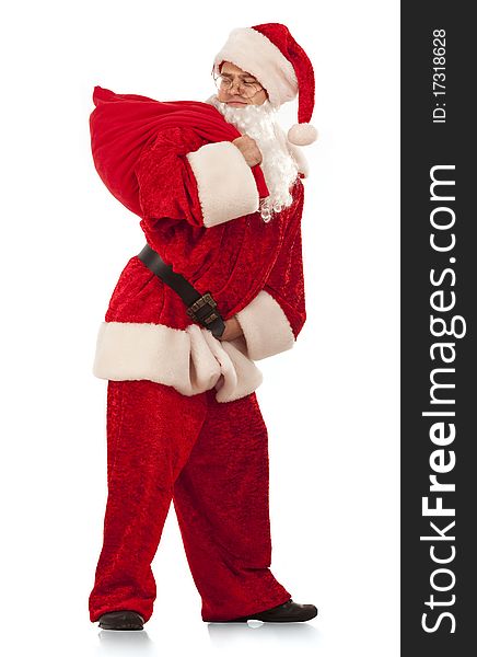 Funny Santa Clause carrying a heavy sack with gifts. Isolated on white.