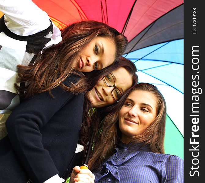 Happy smiling girlfriends stay under colourful umbrella. Happy smiling girlfriends stay under colourful umbrella