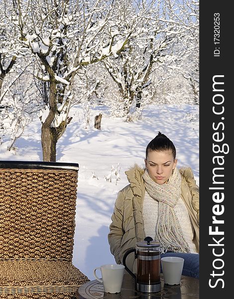 Young female preparing to drink tea, trees with snow on branches in background. Young female preparing to drink tea, trees with snow on branches in background