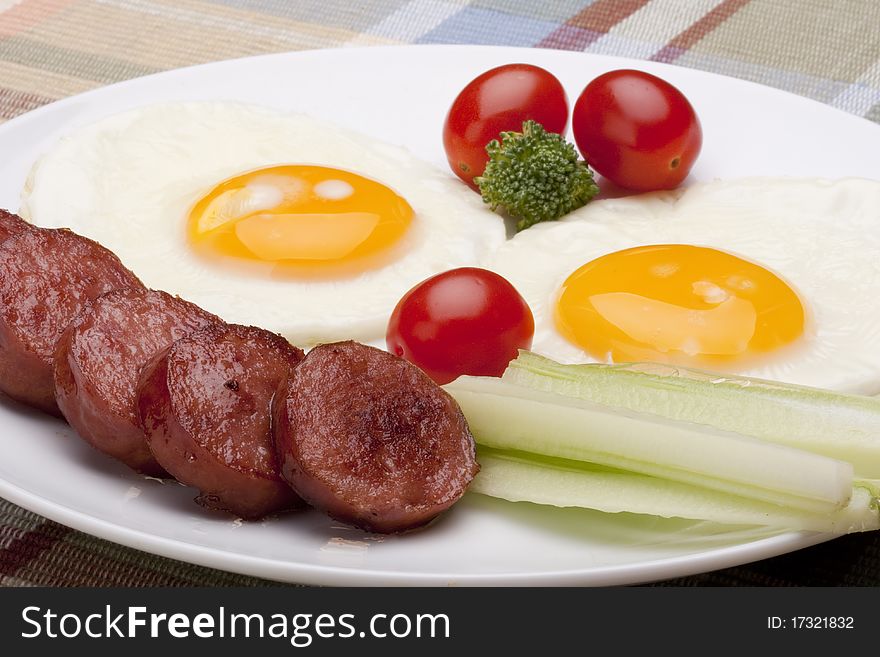 Fried eggs with fried sausage and vegetables.