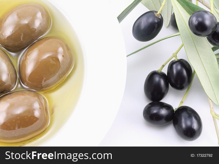 Olives in a bowl with olive oil and olive tree branch