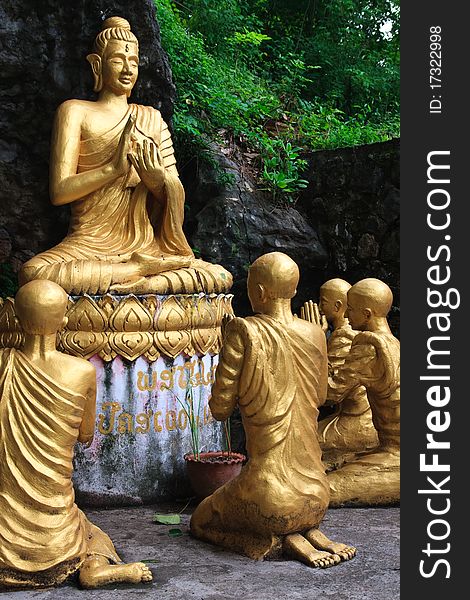 Gold sitting buddha surrounded by monk students