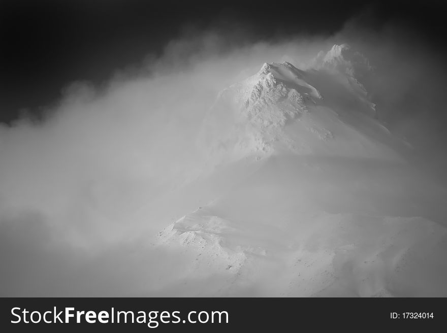 Clouds hovering around a snowy mountain peak, Mt. Hood