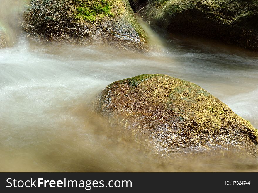 Wet stones lying in the fast stream. Wet stones lying in the fast stream