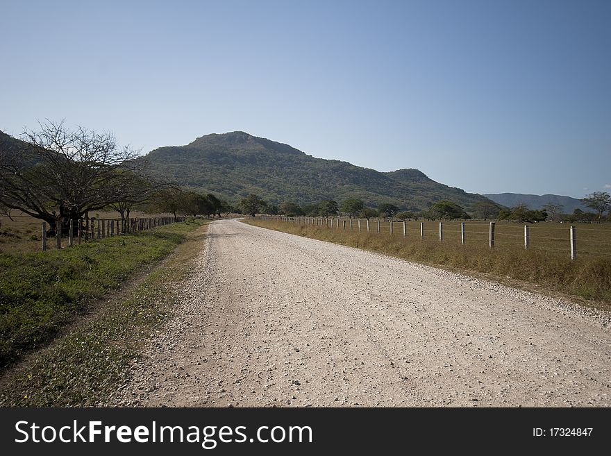 Gravel road across grassland with mountain in the background. Gravel road across grassland with mountain in the background.