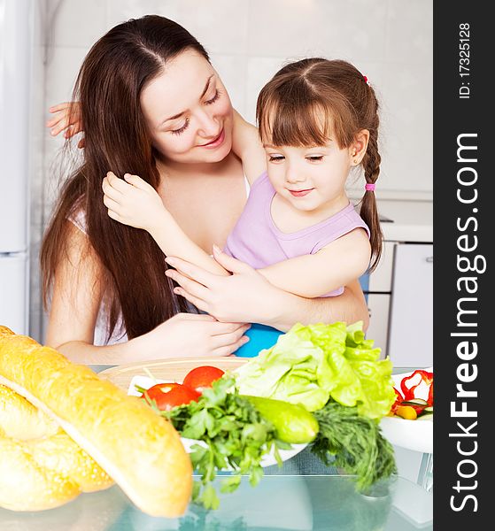 Young mother and her five year old daughter cook together on the kitchen at home. Young mother and her five year old daughter cook together on the kitchen at home