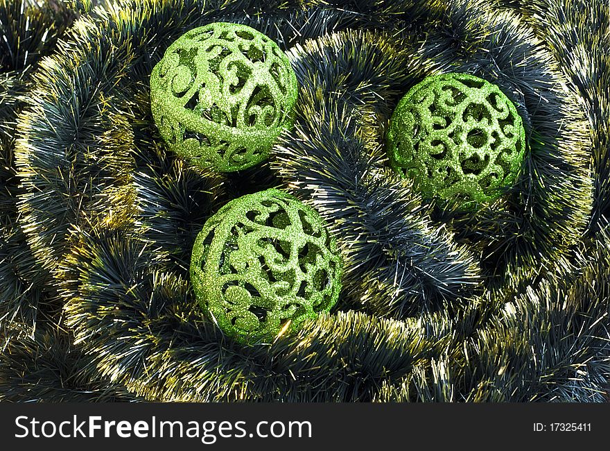 Green carved christmas balls on tinsel background