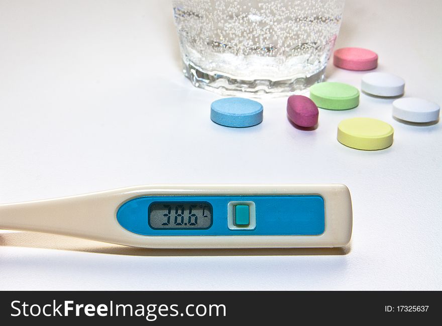 Centigrade thermometer, glass of water and colored pills. Centigrade thermometer, glass of water and colored pills