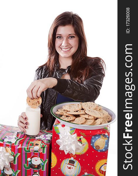 A woman is leaning on a stack of presents dunking a cookie in her milk. A woman is leaning on a stack of presents dunking a cookie in her milk.