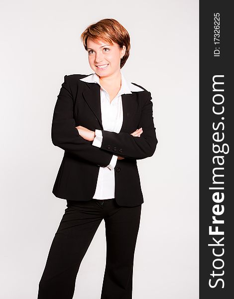 Beautiful businesswoman with her arms crossed on light grey background
