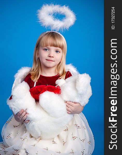 Angelic girl holding white bear. Studio shot