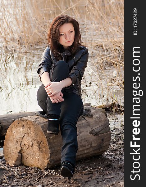 A beautiful girl is sitting on a stump