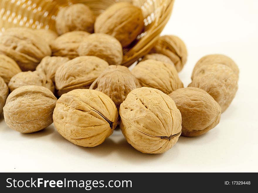 Wicker basket with nuts in the foreground on white background