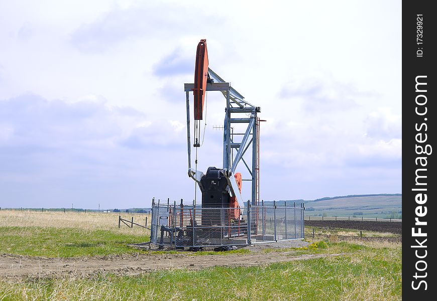 Oil pump in a fenced area located in a barren farmers field. Oil pump in a fenced area located in a barren farmers field.