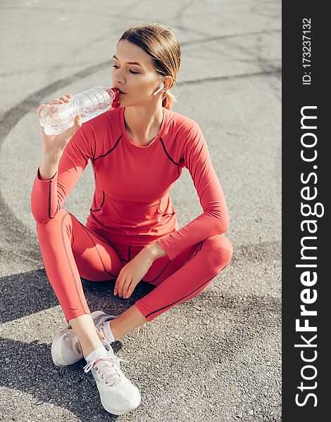 Fit young lady drinking water after workout.