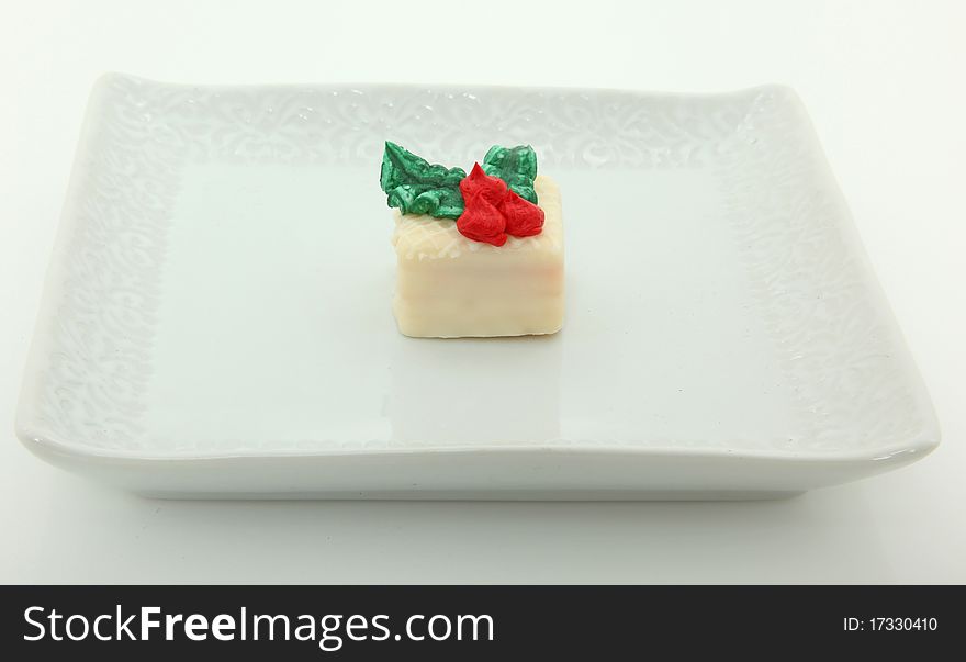 Single Petit Four On White Plate Over White Background. Single Petit Four On White Plate Over White Background