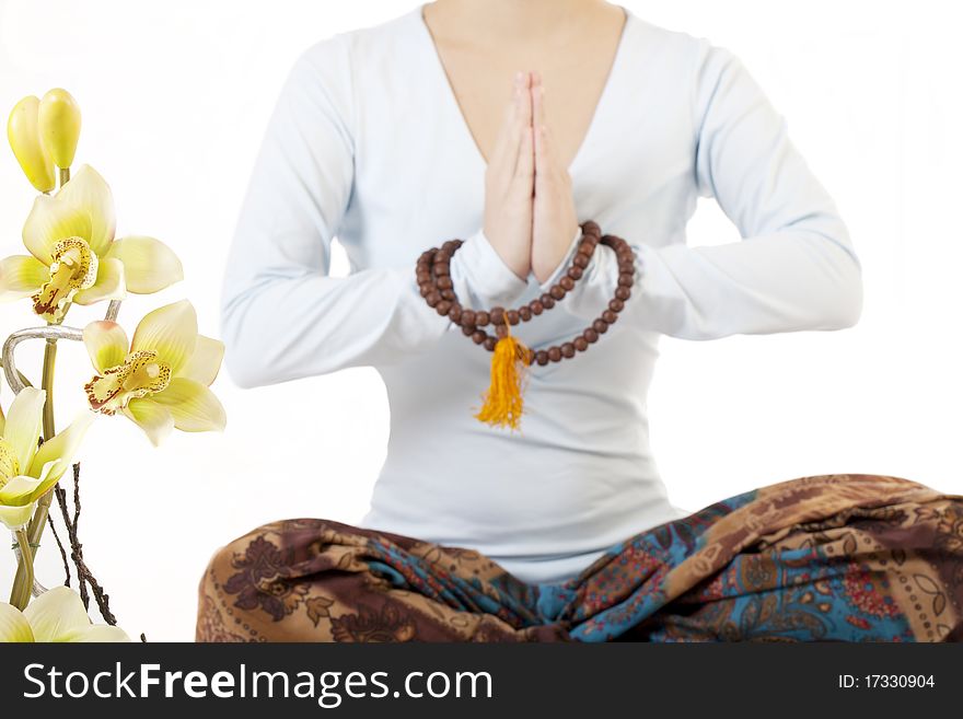 Girl meditating on a white background with the colors of orchids and a rosary