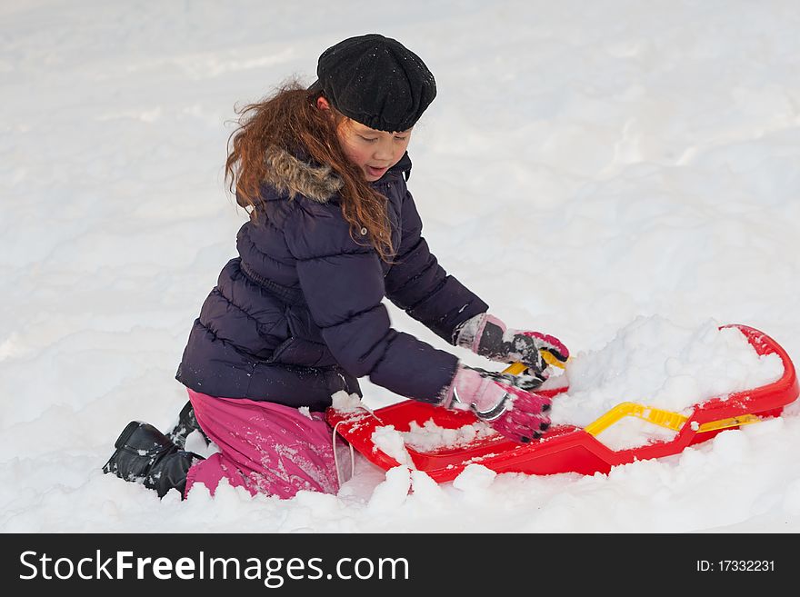 Girl with toboggan in the snow, leisure activity at winter time