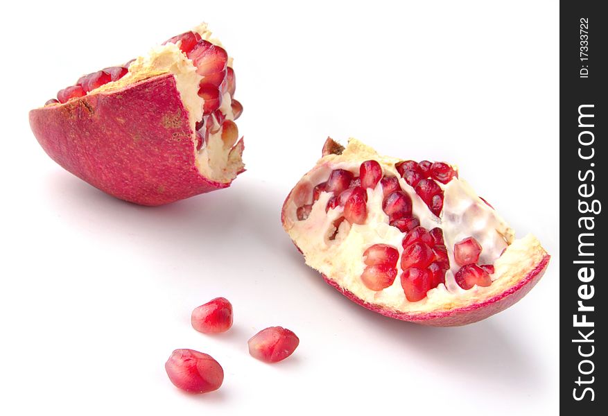 Parts of pomegranate with grains in foreground against white. Parts of pomegranate with grains in foreground against white
