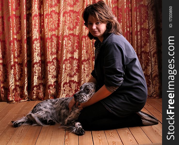 Woman with English setter sitting on the floor against red curtain; dramatic edge lighting with hard shadows. Woman with English setter sitting on the floor against red curtain; dramatic edge lighting with hard shadows