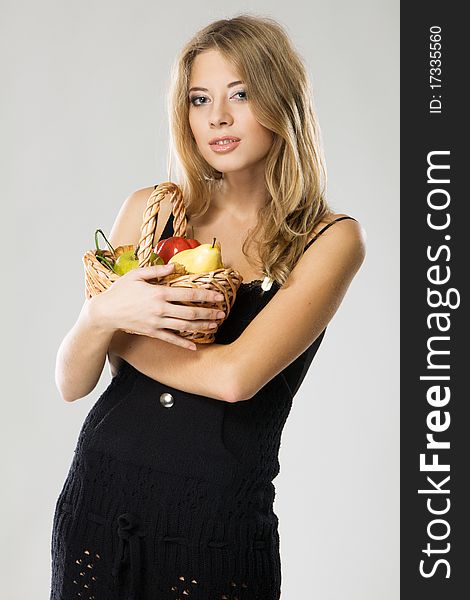 Beautiful lady with basket full of fruits, gray background