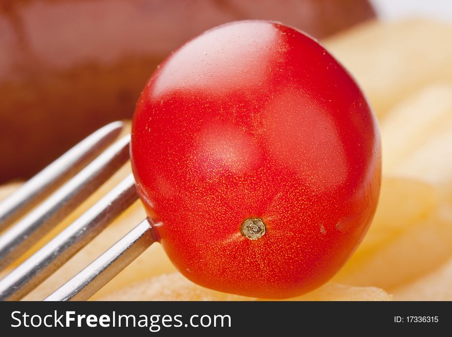 Ripe tomato in a plate with a fried potato.