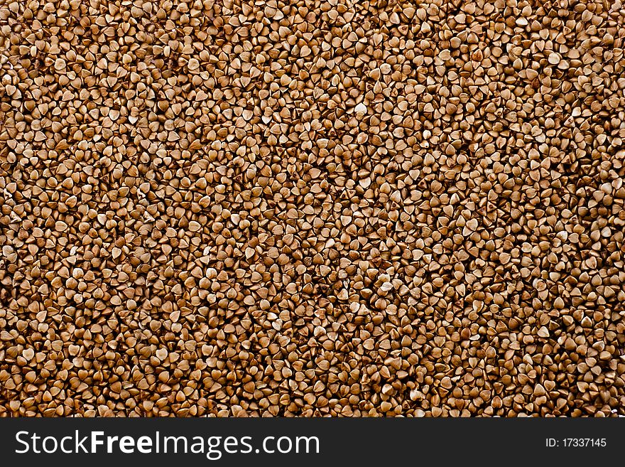 Scattered raw buckwheat background, light brown color