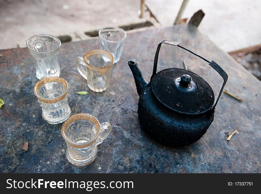 A soot-blackened tea pot and empty tea cups. A soot-blackened tea pot and empty tea cups.