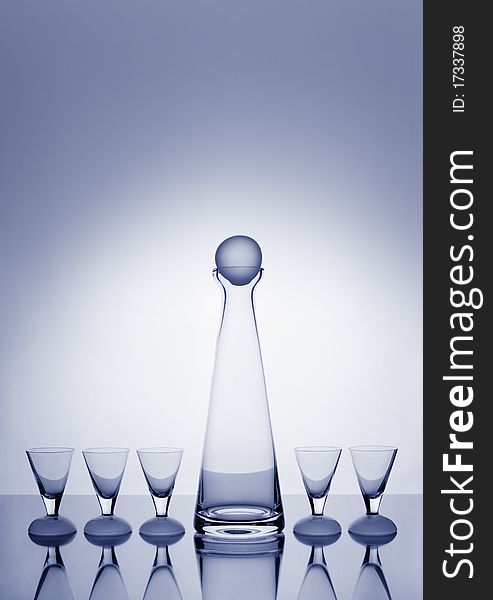 Modern, slim decanter and five glasses toned blue and backlit with a halo and plenty of copy space. Modern, slim decanter and five glasses toned blue and backlit with a halo and plenty of copy space.