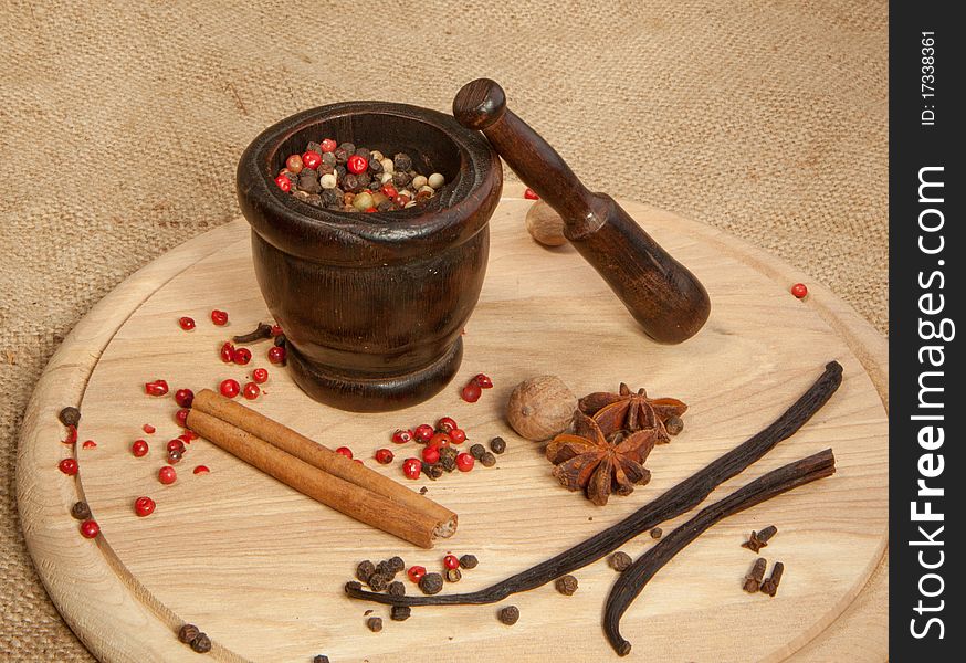 Mix of the spices on the wooden desk with old mortar. Mix of the spices on the wooden desk with old mortar