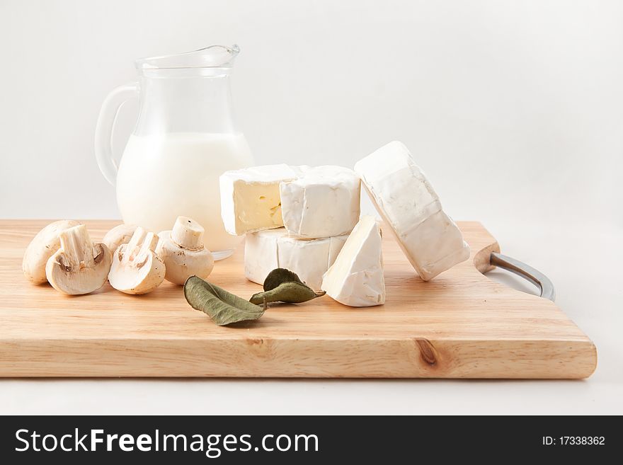 Still-life with white cheese, milk and field mushrooms on the wooden desk