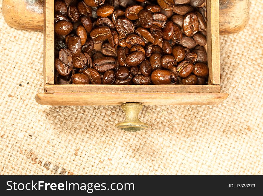 Fragrant fried coffee beans in the old wooden coffee grinder. Fragrant fried coffee beans in the old wooden coffee grinder