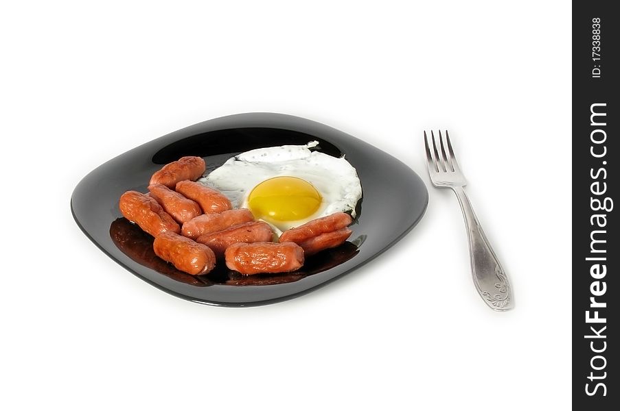 Breakfast (egg and sausage on a black dish isolated on white background).