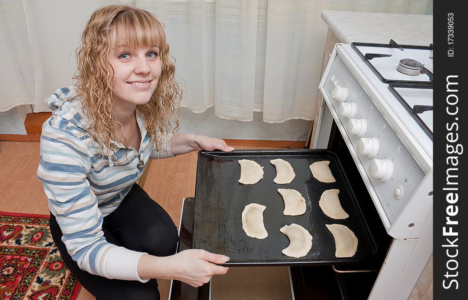 The girl puts pies in an oven for cooking