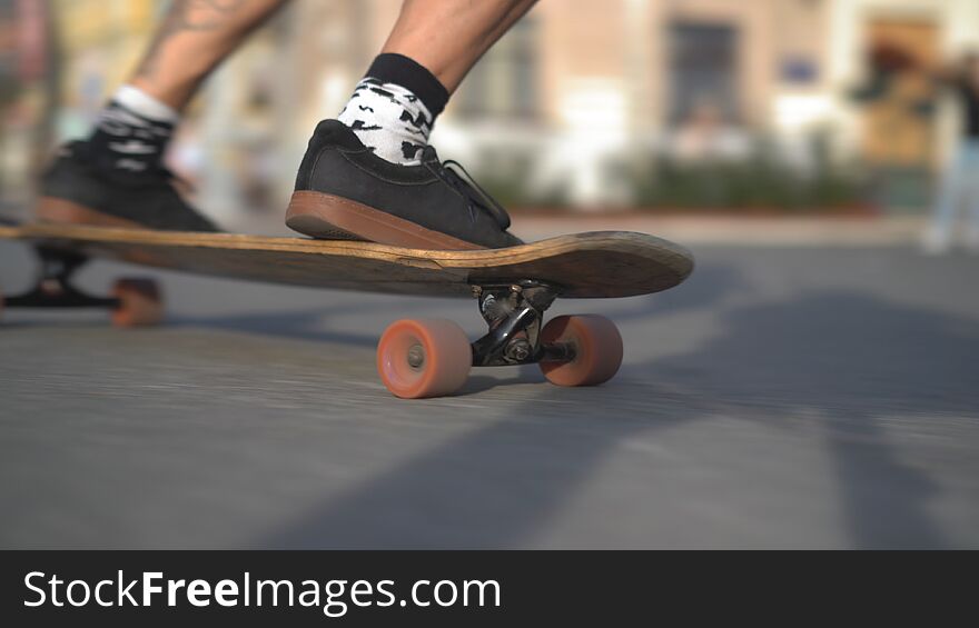 The Legs Of A Light-skinned Man Rushing Forward On A Longboard. Motion Close-up Concept.