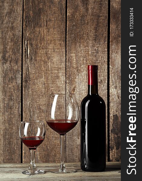 Glass and bottle with delicious red wine on table against wooden background. creative photo.